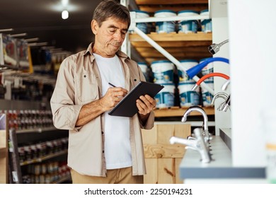 Elderly man working in a hardware store taking inventory. Small business concept. - Powered by Shutterstock