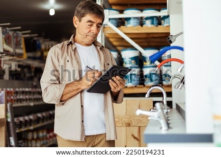 Elderly man working in a hardware store taking inventory. Small business concept.
