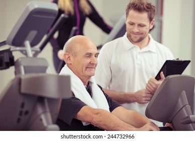 Elderly man working out in a gym with a personal trainer in a healthy lifestyle and fitness concept