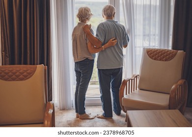 An elderly married couple just arrived at the hotel, looking through the window of their luxury apartment - Powered by Shutterstock