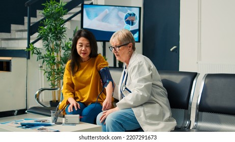 Elderly Medic And Asian Woman Doing Hypertension Measurement With Tonometer At Health Center. Checking Pulse Pressure With Cardiology Test Instrument, Having Medical Appointment.