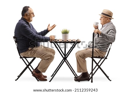 Elderly men drinking coffee and sitting at a cafe table isolated on white background