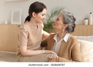 Elderly middle mother sitting on couch with joy holding adult daughter on knees. Happy trusted relations. Family concept.