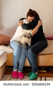 Elderly Mother Embrace And Hug Adult Daughter With Little Dog Sitting In Their Lap. Genuine Moment Of Family Love. 