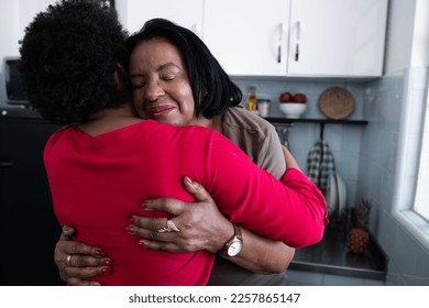 Elderly mother embraces daughter in kitchen at home - Powered by Shutterstock