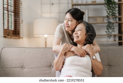 Elderly mother and grown daughter holding hands sitting on the sofa hugging. - Shutterstock ID 2219278551