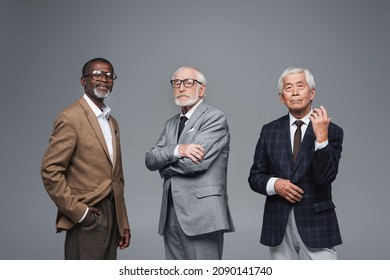 Elderly Multiethnic Business Partners In Formal Wear Looking At Camera While Standing Isolated On Grey