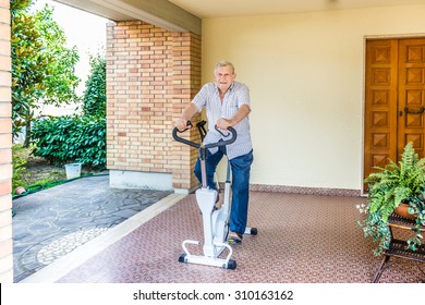 Elderly Octogenarian Male Keeps Fit By Doing Exercise Bike On The Patio Of The House