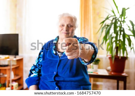 Elderly old woman shows a fig hand gesture