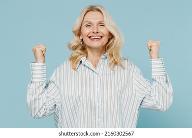 Elderly Overjoyed Excited Fun Cool Caucasian Woman 50s Wear Striped Shirt Do Winner Gesture Clench Fist Isolated On Plain Pastel Light Blue Color Background Studio Portrait. People Lifestyle Concept