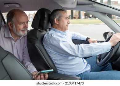 elderly passenger in back seat showing smartphone to car driver-concept of transportation, cab, taxi and technology