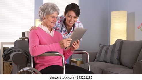 Elderly Patient And Asian Nurse Talking With Tablet