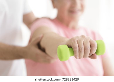 Elderly Patient Holding A Minor Dumb-bell In Her Right Hand During Isometric Physiotherapy