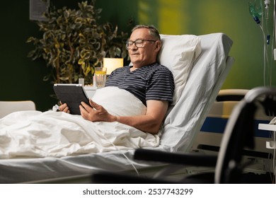 An elderly patient in a hospital bed reads a poetry collection on his tablet, smiling at the verses. - Powered by Shutterstock