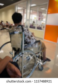 Elderly Patients Sitting On Wheelchair Waiting For The Doctor In Front Off Emergency Room, At Hospital, With Space For Text, Blur Background. Selective Focus.