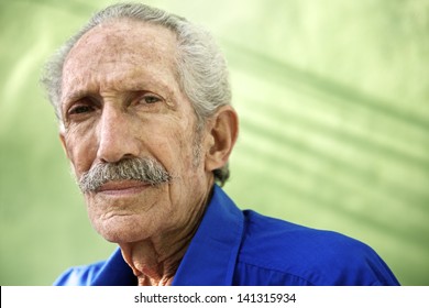 Elderly People And Emotions, Portrait Of Serious Senior Caucasian Man Looking At Camera Against Green Wall