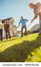 Elderly People Having Fun Playing Mini Golf At The Backyard Lawn, Spending Sunny Summer Day Outdoors