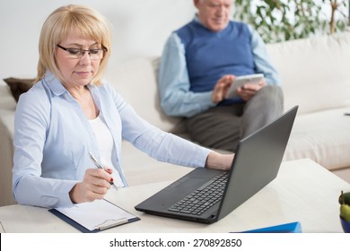 Elderly People Working On Laptop And Tablet At Home