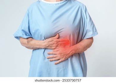 Elderly person in blue hospital gown holding stomach in pain. Stomach pain, hospital gown, and elderly care. Elderly patient with stomach ache. Elderly patient feel stomach abdominal pain.  - Powered by Shutterstock