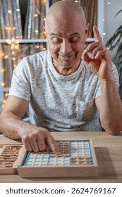 elderly person is deeply engrossed in solving challenging Sudoku puzzle, mental stimulation and enjoyment classic game provides, wooden Sudoku puzzle board as adult thoughtfully considers next move