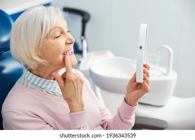 Elderly Person With Mirror Pushing Her Tooth With Finger