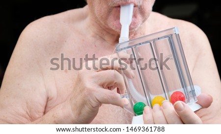 Elderly person using incentive spirometer for lung  after heart surgery so that lung competent capacity and strong after recovery