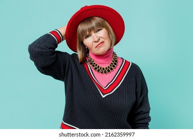 Elderly Puzzled Caucasian Confused Sad Woman 50s Wearing Necklace Shirt Red Hat Look Aside Scratch Hold Head Isolated On Plain Pastel Light Blue Background Studio Portrait. People Lifestyle Concept