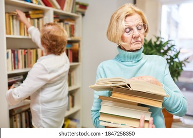 Elderly Researches Or Reads A Book In The Library In The Nursing Home