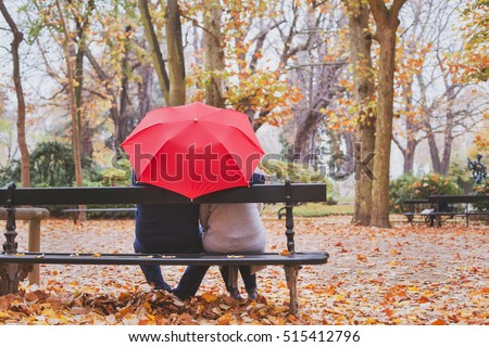 elderly retired couple sitting together on the bench in autumn park, love concept