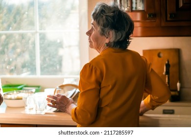 Elderly Retired Gray-haired Woman Having A Good Time In Her House, Active In Her Old 80+ Age, Washing Dishes In A Cozy Kitchen, Cleaning. A Happy Grandmother In A Yellow Blouse, Young At Heart.