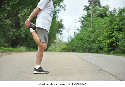 Elderly Retired Man Is Stretching His Legs Before Running Or Jogging, Concept Warm Up Exercise Prevent Injury In Elderly People