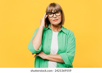 Elderly sad disappointed upset blonde woman 50s years old wear green shirt glasses casual clothes look camera hold scratch head isolated on plain yellow background studio portrait. Lifestyle concept - Powered by Shutterstock