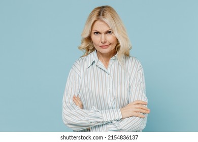 Elderly sad dissatisfied indignant displeased caucasian woman 50s wear striped shirt hold hands crossed folded isolated on plain pastel light blue background studio portrait. People lifestyle concept