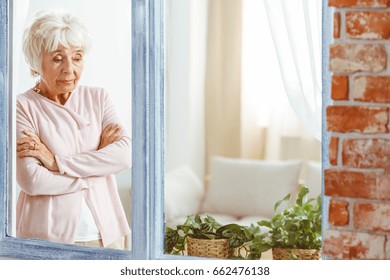 Elderly Sad Woman Looking Down Wondering By The Window