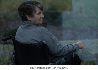 Elderly sad woman looking through the window - Powered by Shutterstock