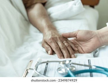 Elderly senior aged patient on bed with geriatric doctor holding hands for trust and nursing health care, medical treatment, caregiver and in-patient ward healthcare in hospital  - Shutterstock ID 2349874929