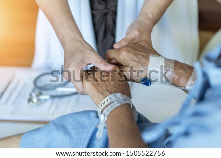 Elderly senior aged patient on bed with geriatric doctor holding hands for trust and nursing health care, medical treatment, caregiver and in-patient ward healthcare in hospital  Stockfoto © 