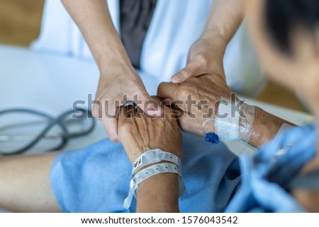 Elderly senior aged patient on bed with geriatric doctor holding hands for trust and nursing health care, medical treatment, caregiver and in-patient ward healthcare in hospital  Stockfoto © 