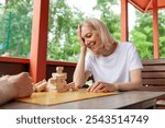 elderly senior couple playing board game and building a tower with wooden bricks outdoors in the park, old woman shows facepalm and loses by making a mistake in jenga