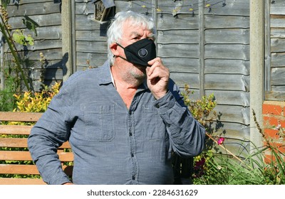 Elderly or senior man adjusting his face mask. Face mask to protect him from a virus.  - Powered by Shutterstock