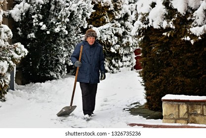 Elderly Senior Man With A Snow Shovel Outdoors.