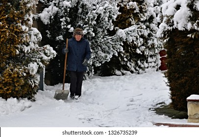 Elderly Senior Man With A Snow Shovel Outdoors.