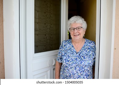 elderly senior woman opening front door of house and welcoming people at home  - Powered by Shutterstock