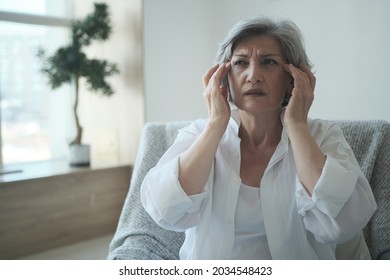 Elderly senior woman suffering from migraines and headaches, memory lapses and sleep difficulties. A depressed, melancholy 70-year-old woman has long covid symptoms.