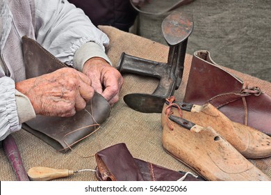 elderly shoemaker makes artisan shoes on an old bench with old tools for leather working