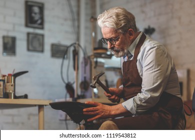 An elderly shoemaker at work in a workshop - Powered by Shutterstock