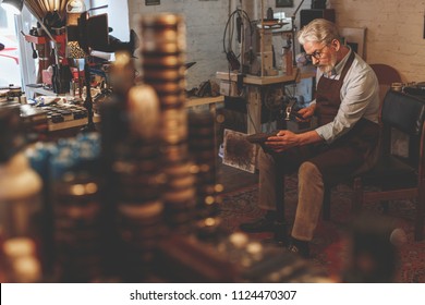 An elderly shoemaker at work in a workshop - Powered by Shutterstock