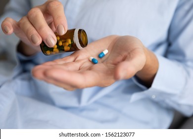 Elderly sick ill woman hold two pills on hand pouring capsules from medication bottle take painkiller supplement medicine, old senior people pharmaceutical healthcare treatment concept, close up view - Shutterstock ID 1562123077