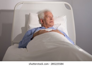 Elderly Sick Male Patient Lying In Hospital Bed