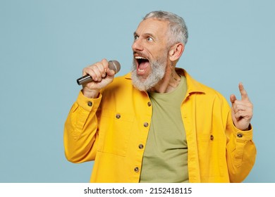 Elderly singer gray-haired mustache bearded man 50s wear yellow shirt sing song in microphone at karaoke club isolated on plain pastel light blue background studio portrait. People lifestyle concept - Powered by Shutterstock